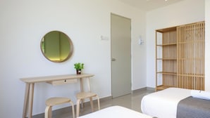 Una habitación de hotel con escritorio, dos sillas, cama, armario y espejo.