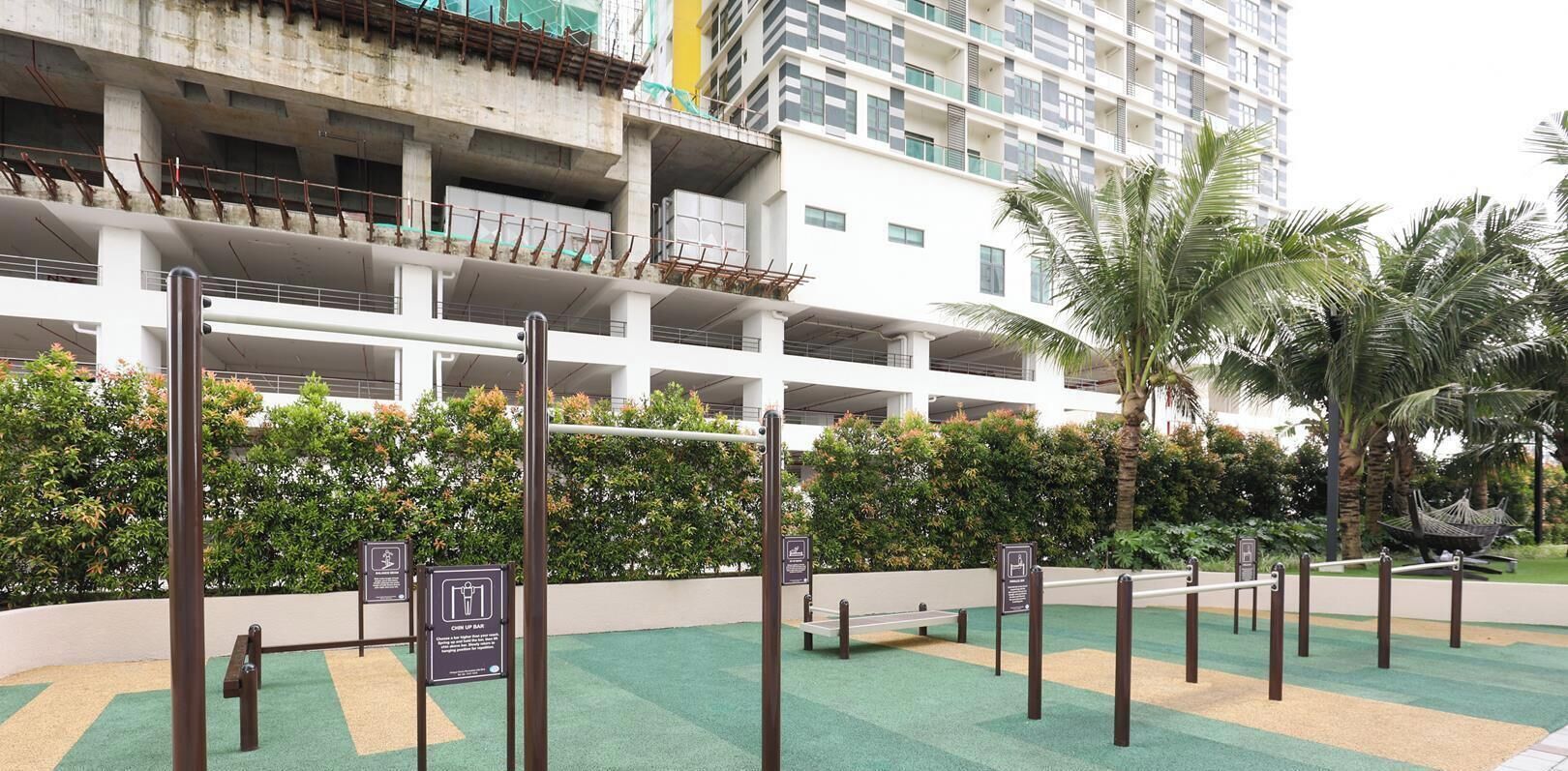 A multi-story building with a parking structure, surrounded by greenery and palm trees.