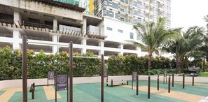 Un edificio de varios pisos con una estructura de estacionamiento, rodeado de vegetación y palmeras.
