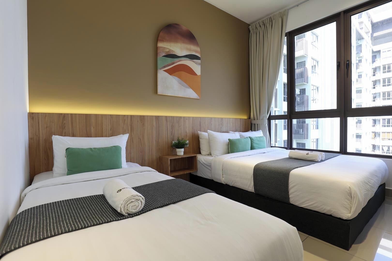 A hotel room with two beds, a large window, and a wall-mounted artwork.
