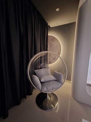 A modern room with a hanging chair, a large circular light fixture, and a black curtain. - Bali Deluxe Melaka By I Housing  (Malacca City)