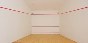 Una habitación con suelo de madera y paredes blancas, con líneas rojas que marcan la distribución de una cancha deportiva.