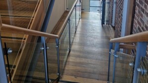 Un intérieur moderne avec un escalier en bois, des rampes en verre et un mur en briques.