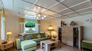 Una sala de estar con sofá, mesa de centro, lámpara, aparador y ventana con cortinas.