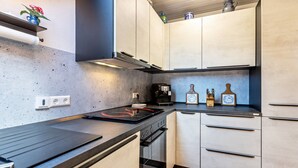 Une cuisine moderne avec un plan de travail noir, des appareils en acier inoxydable et des meubles de couleur claire.