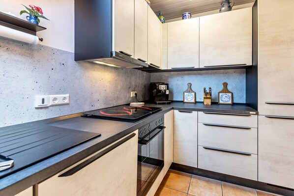 A modern kitchen with a black countertop, stainless steel appliances, and light-colored cabinetry.
