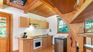 Ein Holzblockhaus-Interieur mit einer Küche, die Holzschränke, einen Herd und ein Spülbecken zeigt.