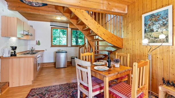 Ein Holzinnenraum mit Küche, Essbereich und einer Treppe.