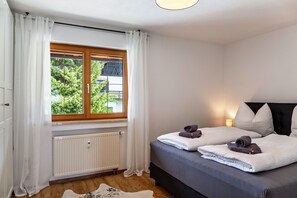 Une chambre à coucher avec un lit, une fenêtre avec des rideaux, un radiateur et un tapis en peau de vache.