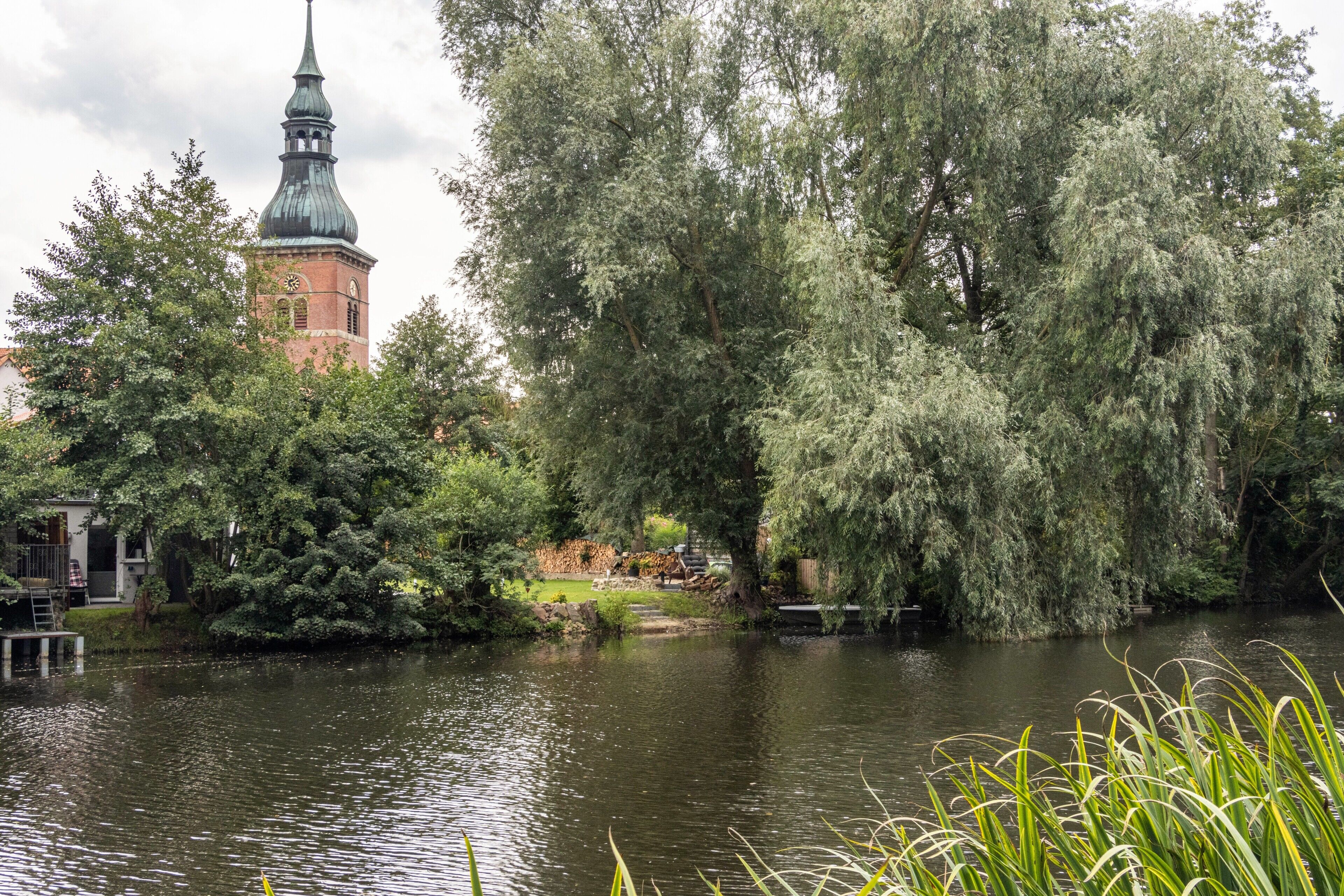 Een rustgevende rivieroever met een historisch pand en een klokkentoren.