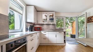 A modern kitchen with white cabinets, a built-in oven, and a red microwave. - Apartment by the Park Lake with Lake Access (Bad Bodenteich)