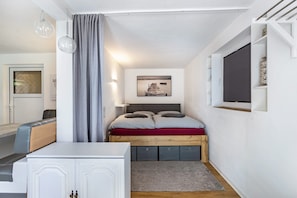 Un dormitorio con cama, mesitas de noche, armario, ventana y un cuadro en la pared.