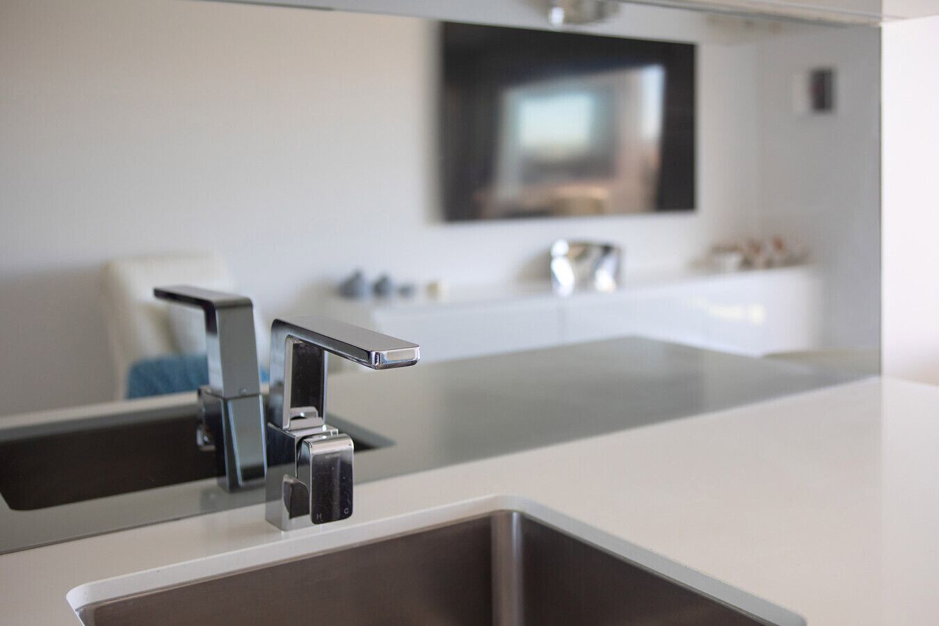 A modern kitchen with a double sink, a countertop, and a wall-mounted television.