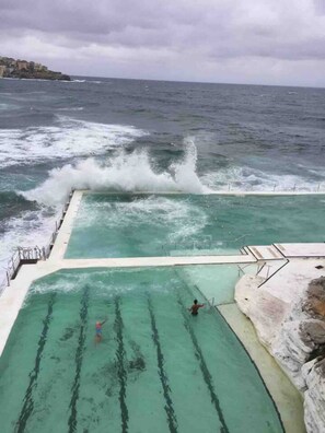 Una piscina con vistas al océano y olas rompiendo en la orilla.