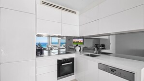 Eine moderne Küche mit Geschirrspüler, Kaffeemaschine und Meerblick.