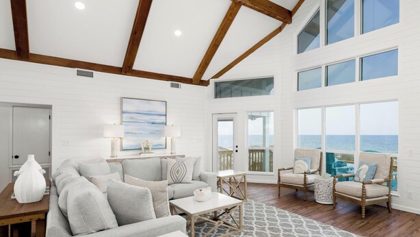 A spacious living room with a large window overlooking the ocean, a cozy seating area, and a wooden ceiling. - Modern Beach Front Home with Private Beach Access | Trillion Dollar View by Kaiser (Gulf Shores)