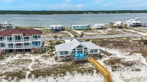 A beachfront property with multiple houses, a wooden boardwalk, and a view of the ocean. - Modern Beach Front Home with Private Beach Access | Trillion Dollar View by Kaiser (Gulf Shores)