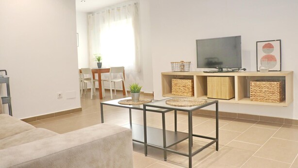 Un salon moderne comprenant un canapé, une table basse, un téléviseur et un coin repas avec des chaises et une table.