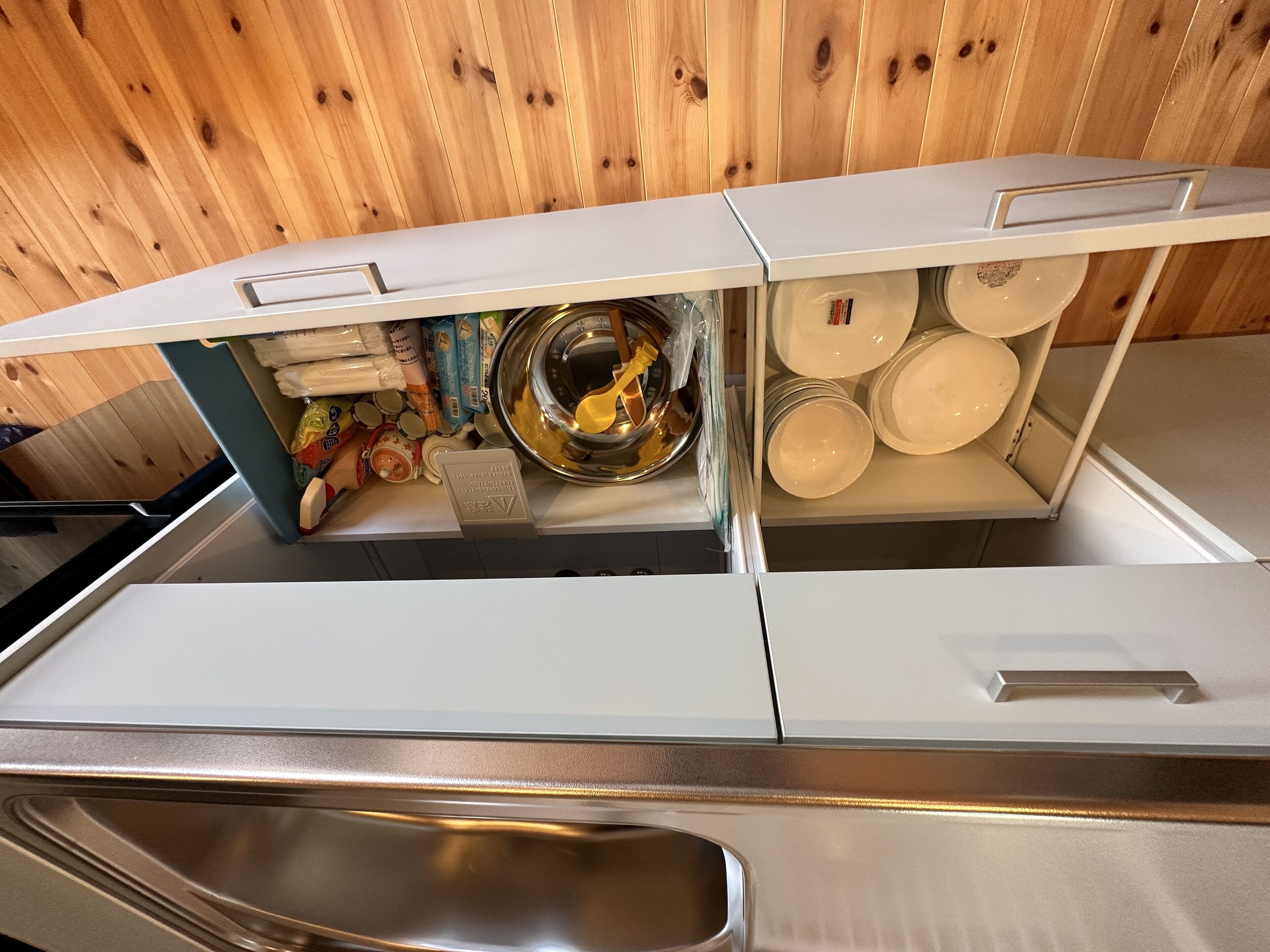 A kitchen with a stainless steel sink, a built-in oven, and a wooden wall.