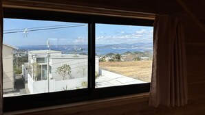 A room with a large window overlooking a residential area and a body of water. - shirahamakashibessoK-32 (Shirahama)