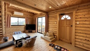 A wooden cabin interior with a TV, sofa, and dining table. - shirahamakashibessoK-32 (Shirahama)