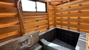 A wooden cabin interior with a corner bathtub, wooden walls, and a window. - shirahamakashibessoK-32 (Shirahama)