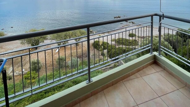 Un balcon avec vue sur la mer et les montagnes au loin.