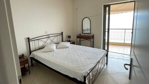 Une chambre à coucher avec un lit, une table de chevet, un miroir et une fenêtre donnant sur un balcon.