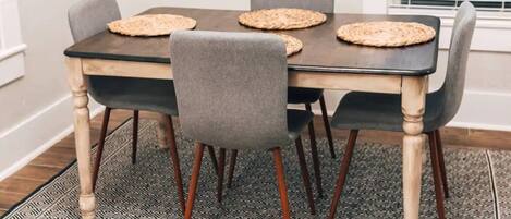 A dining table with four chairs, a black tablecloth, and woven placemats.