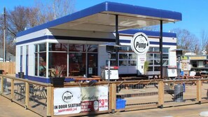 Un camión de comida con decoración azul y blanca, que muestra un logo 'Pump' y un letrero anunciando 'Comedor Interior' y 'La Cervecera Más Antigua de Estados Unidos' con una oferta especial.