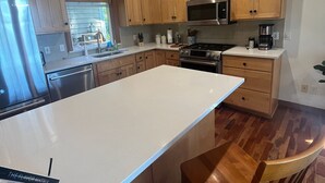Une cuisine moderne avec des meubles en bois, un réfrigérateur en acier inoxydable, un four à micro-ondes et une cuisinière.