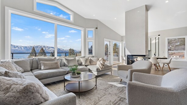 A spacious living room with a large sectional sofa, a round coffee table, and a fireplace. - Luxury Kelowna House w/Pool and Sauna (West Kelowna)