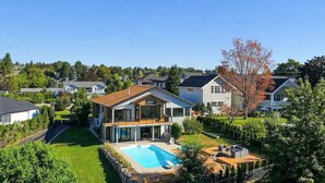 A modern two-story house with a large backyard, a swimming pool, and a deck area. - Luxury Kelowna House w/Pool and Sauna (West Kelowna)