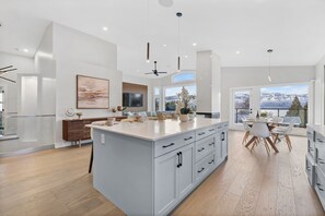 A modern kitchen with a large island, white cabinetry, and a dining area with a view of mountains.
