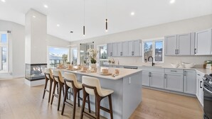 A modern kitchen with a large island, bar stools, and a view of the outdoors. - Luxury Kelowna House w/Pool and Sauna (West Kelowna)
