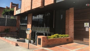 A modern building with a brick facade, large windows, and a gated entrance. - Apartamento con Terraza Privada en la Calleja. A 3 min de la Clinica Reina Sofía (Bogotá)