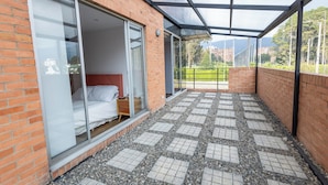 A modern hotel room with a large sliding glass door, a bed, and a view of the outdoors. - Apartamento con Terraza Privada en la Calleja. A 3 min de la Clinica Reina Sofía (Bogotá)