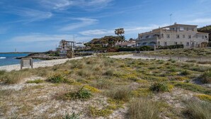 Une propriété située sur la côte, comprenant un grand bâtiment, une plage de sable et une côte rocheuse.