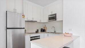 Una cocina moderna con armarios blancos, electrodomésticos de acero inoxidable y un tazón rosa en la encimera.