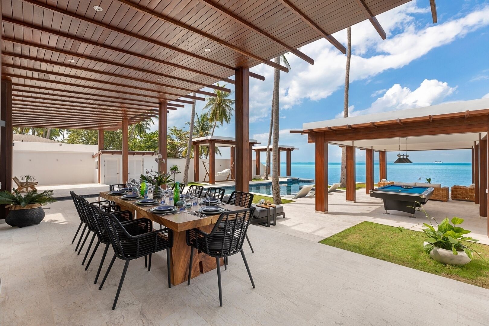 Un espace extérieur aménagé pour les repas, avec une piscine et une vue sur l’océan.