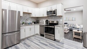 A modern kitchen with white cabinets, stainless steel appliances, and a grey patterned backsplash. - Luxe Family Home/2 kitchens & Living Rooms/Balcony (Louisville)