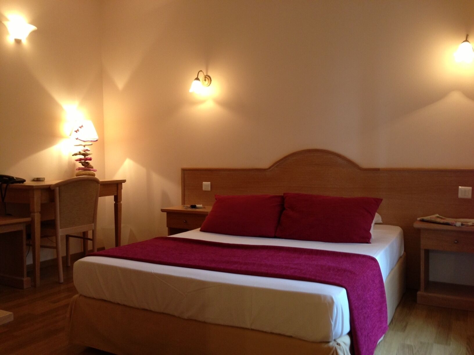 Una habitación de hotel con cama, escritorio y dos mesitas de noche.