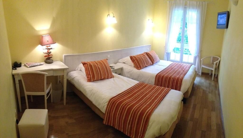 A room with two beds, a desk, a chair, and a lamp.