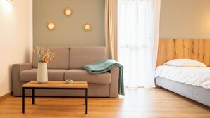 Una habitación con sofá, cama, mesa de centro y elementos decorativos en la pared.