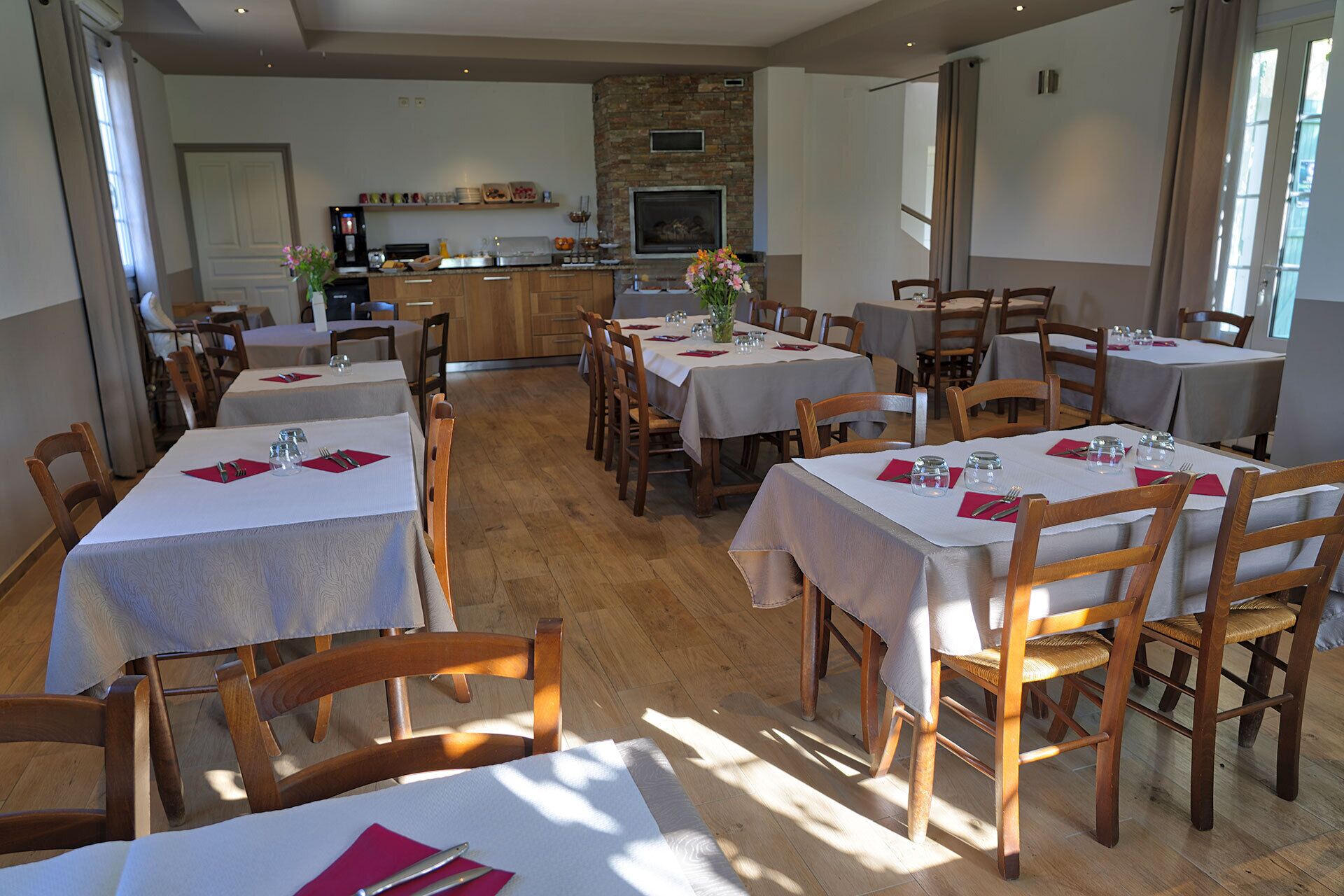 Un restaurant avec plusieurs tables, des chaises en bois et un mur de pierre en arrière-plan.