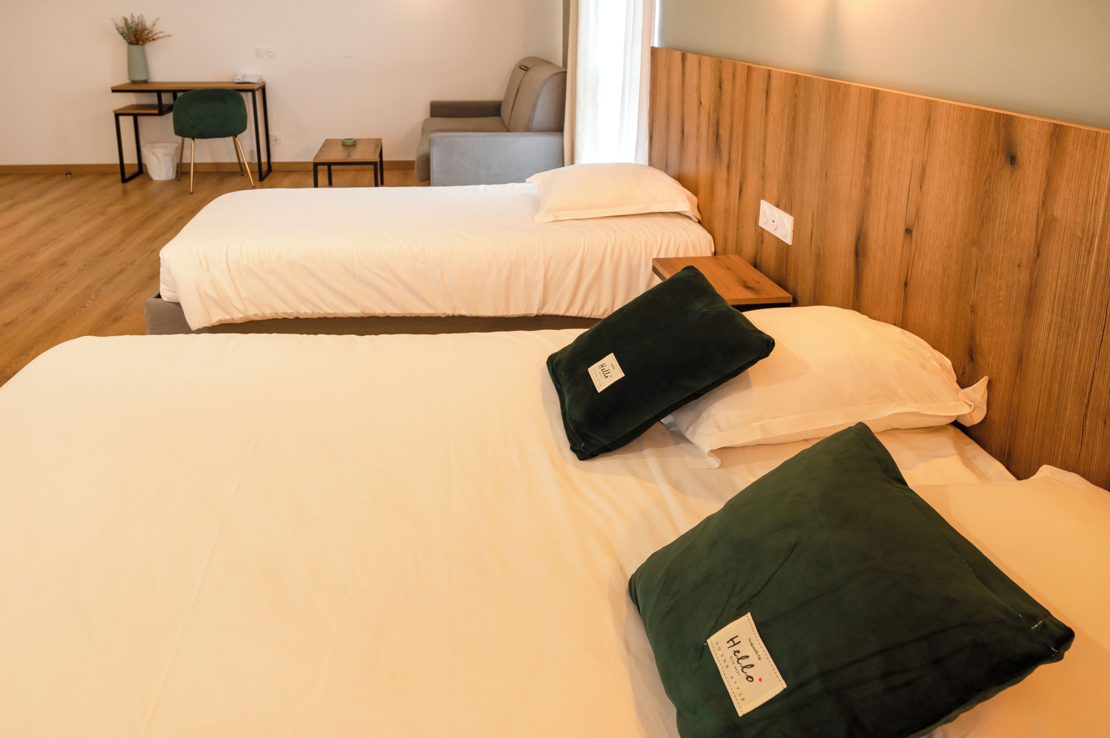 A hotel room with two beds, a desk, a chair, and a small table.