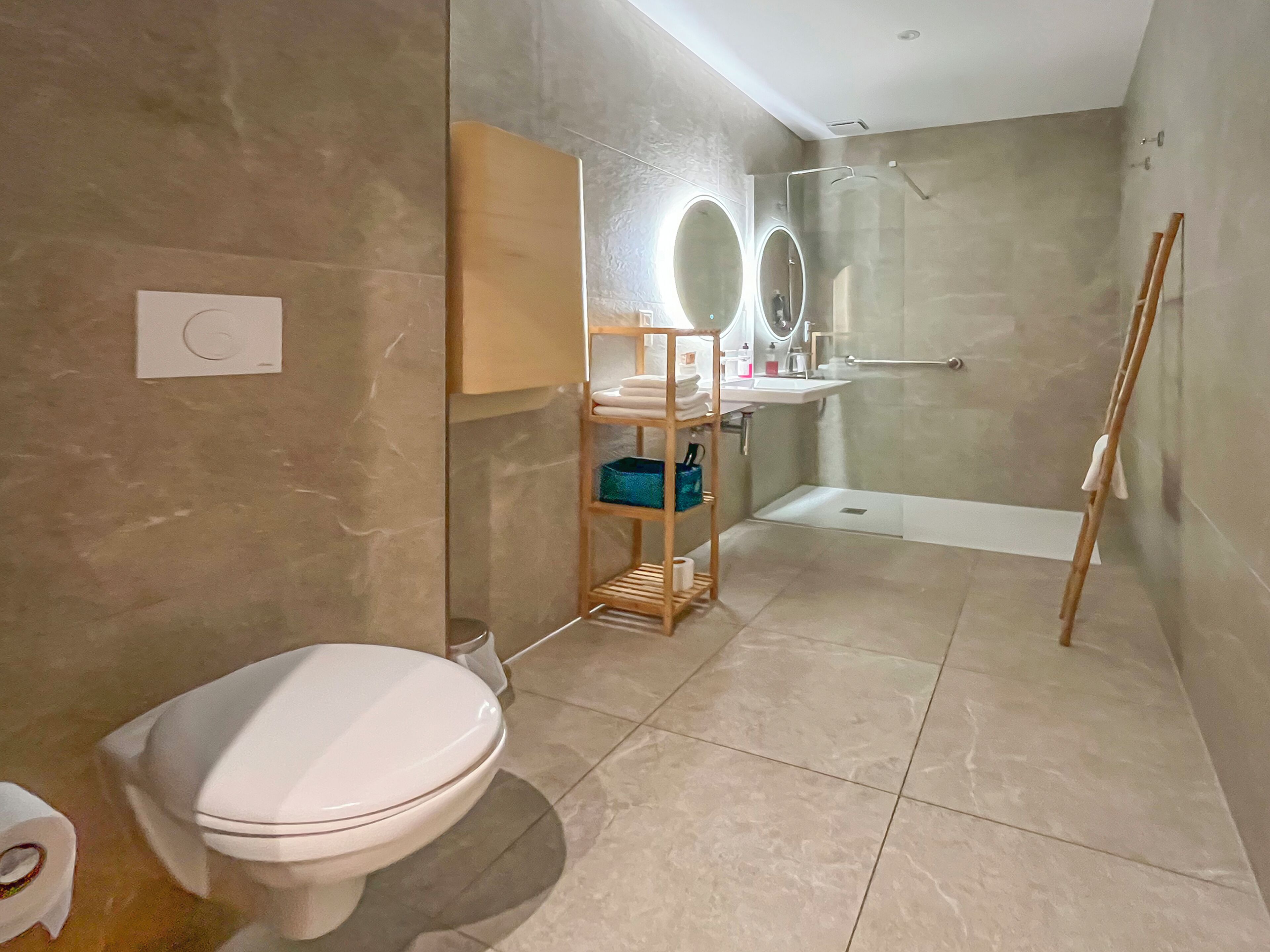 Une salle de bain moderne équipée de toilettes, d’un lavabo, d’une douche et d’un miroir.