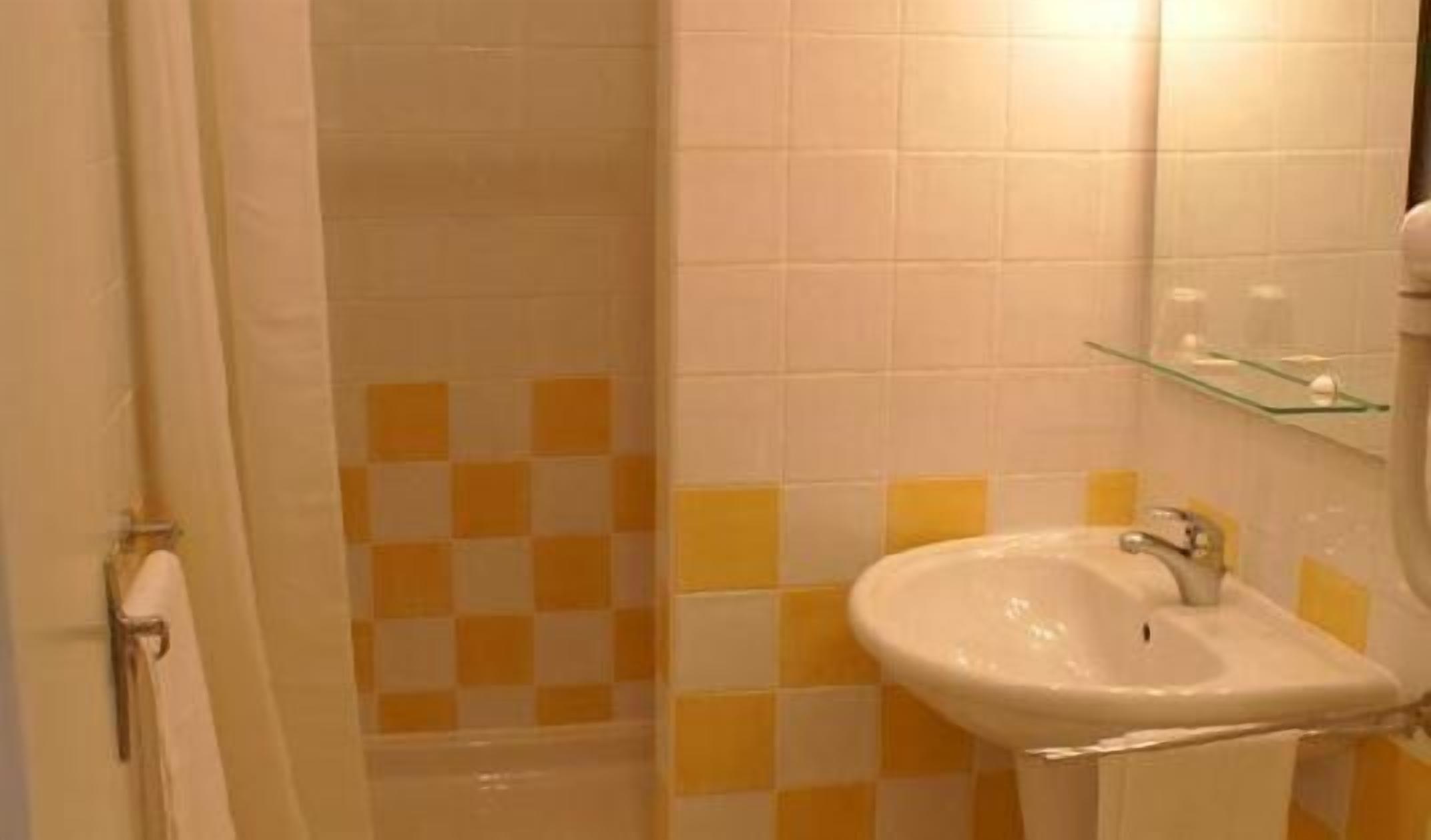 Une salle de bain avec un lavabo, un miroir et des murs carrelés.