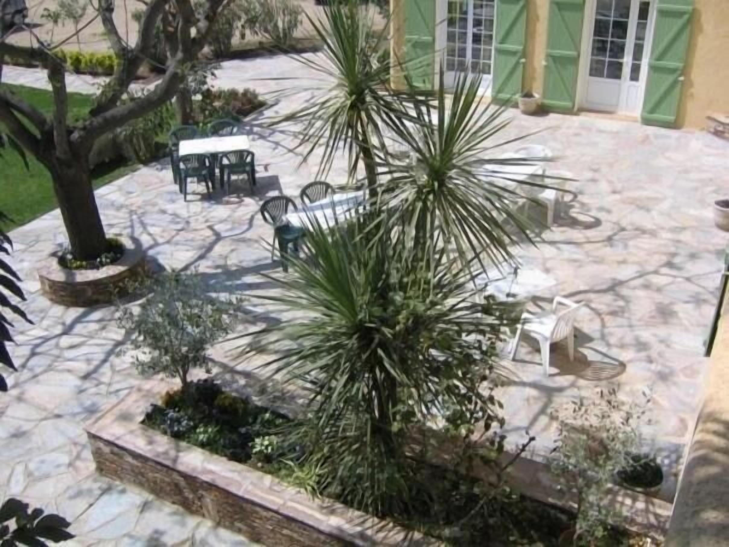 Un patio con suelo de piedra, mobiliario exterior y diversas plantas.