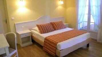 A bedroom with a bed, nightstands, a chair, and a window with curtains.